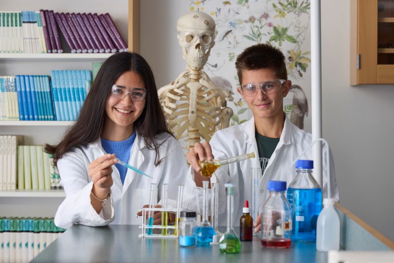 Två elever som håller i provrör och jobbar med ett kemiprojekt.