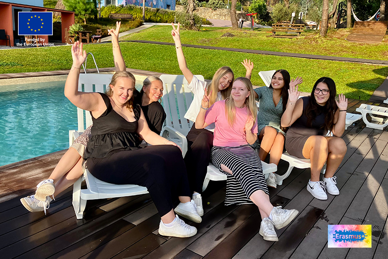 Ett gäng tjejer vinkar framför en pool. I hörnen sitter EU-flaggan och loggan för Erasmus+.